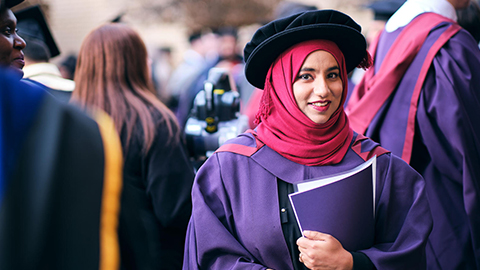 A person wearing a robe and a floppy hat signifying a PhD